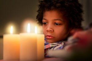 Sad boy looking at candle.